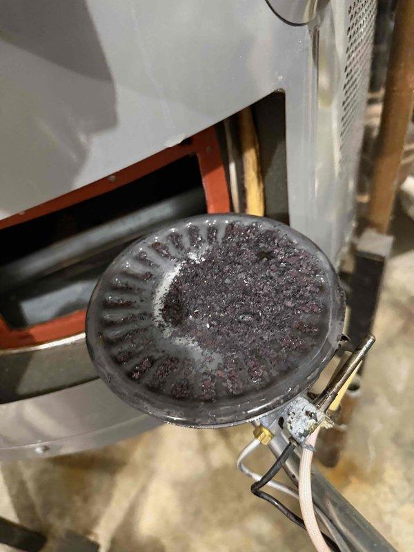 Conducted diagnostic inspection on leaking water heater referred by Ken Shockley. Identified significant corrosion and oxidation on copper pipes with visible turquoise-colored copper oxide formation at connection points. Observed water pooling around base with rust stains indicating ongoing leakage. Noted filter component showing substantial debris buildup requiring maintenance or replacement.