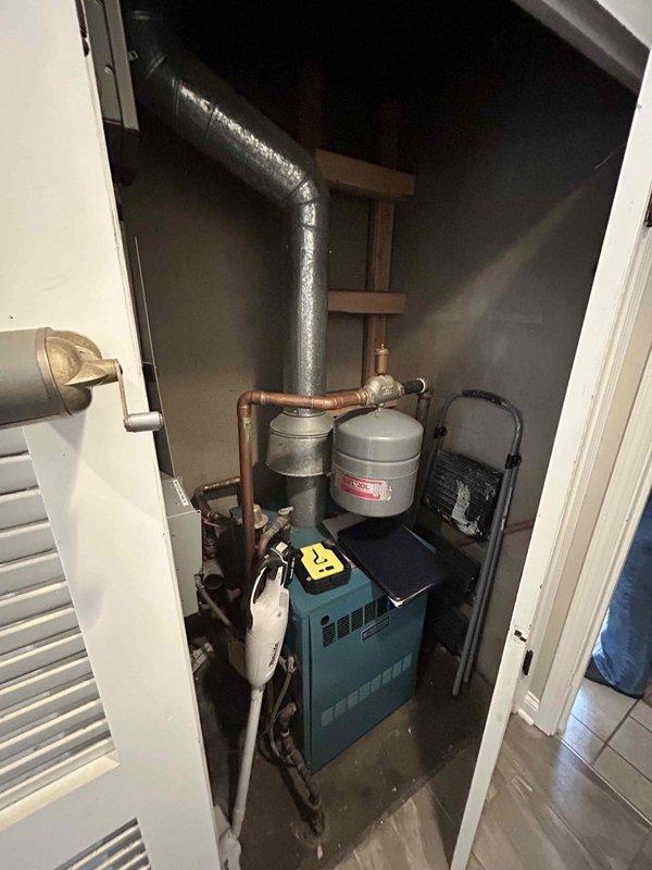 Conducted comprehensive assessment for replacement of 36-year-old AC/air handler system. Evaluated existing outdoor condenser unit showing significant age-related wear and documented the current heating system configuration in utility closet. Noted installation challenges including limited attic access (2'x2' hatch) in ranch-style home with low ceilings, requiring specialized installation planning for the replacement equipment.