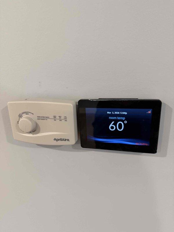 Conducted system start-up and punch list verification for HVAC installation. Documented outstanding items including exposed HVAC wire near thermostat, missing cold air return covers in living room and upper hallway, and dust accumulation on furnace. Verified proper installation of AprilAire humidity control and digital thermostat, and confirmed air filters were correctly installed in the air handler.