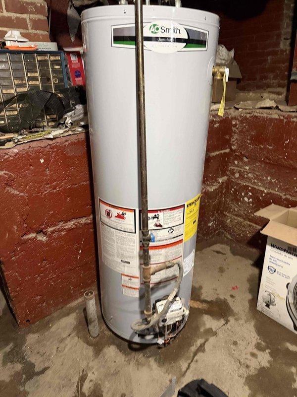 Responded to no water complaint following basement flooding. Inspected AO Smith water heater that customer was unable to restart after water receded. Found water supply connection intact with proper PVC and braided steel line connections, diagnosed pilot/ignition system issue, and successfully restored water heater operation and hot water service to residence.