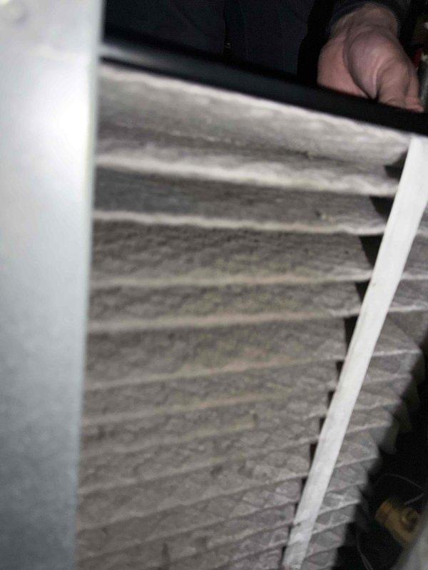 Investigated customer complaint of basement water damage after recent AC activation. Inspected air filtration system and found accumulated particulate matter on pleated filter. Examined copper plumbing configuration with 90-degree elbow joint, noting slight oxidation at soldered connection points where condensation appears to be originating.