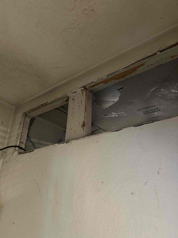 Performed assessment of heat pump air handler for removal to facilitate drywall replacement due to significant water damage. Inspection revealed deteriorated wall/ceiling junction with peeling paint, rotting wood, and visible water damage. Examination of HVAC components showed aging heating coils with discoloration and potential moisture exposure, requiring full system replacement as part of insurance claim.