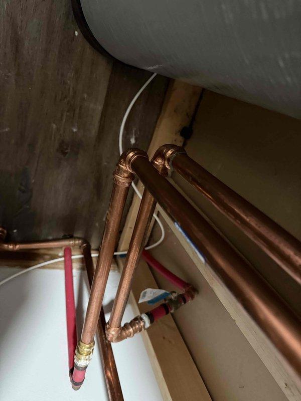 Responded to warranty service call for recently installed tankless water heater with reported leakage. Inspected copper piping connections and found minor leak at an elbow joint. Tightened connection and verified system integrity with no further water accumulation on floor.