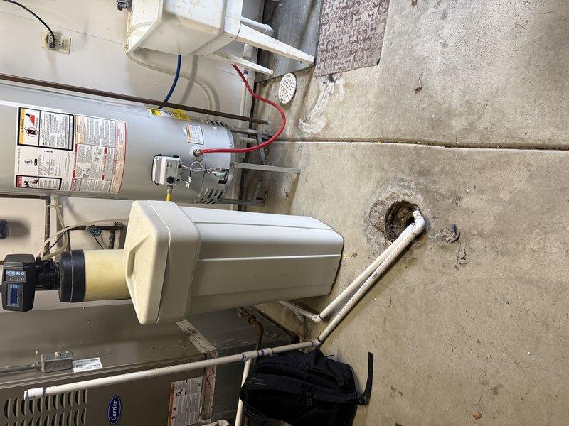 Performed visual inspection of utility room to gather measurements for water softener installation. Documented existing plumbing configuration including PVC drainage pipes and connection points. Evaluated current setup with recently installed HVAC equipment and water heater to determine optimal placement for new water softener system.