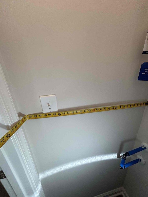 Performed on-site measurements for water softener installation quote in utility area, taking precise wall-to-appliance dimensions with measuring tape. Customer requires financing options for the installation. Photographs were taken to document the installation space and current plumbing configuration to ensure proper equipment sizing and placement.