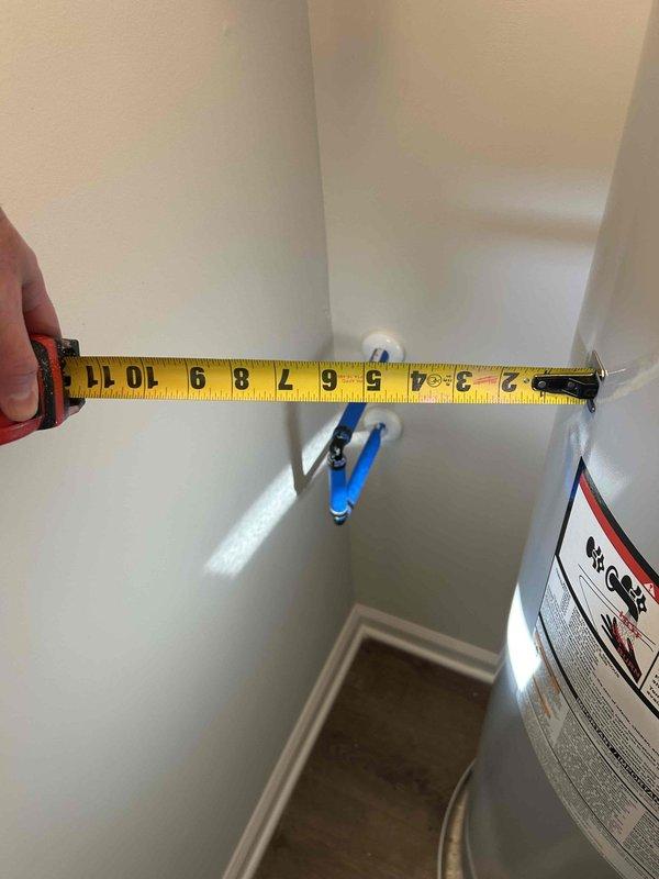 Performed on-site measurements for water softener installation quote in utility area, taking precise wall-to-appliance dimensions with measuring tape. Customer requires financing options for the installation. Photographs were taken to document the installation space and current plumbing configuration to ensure proper equipment sizing and placement.
