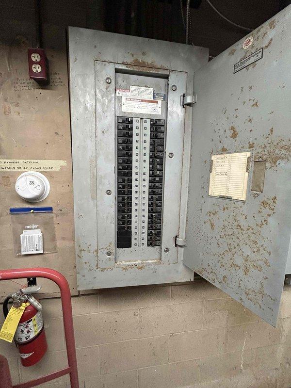 Conducted site assessment at commercial food pantry facility to provide estimate for replacement of two existing furnaces. Inspected current heating equipment and building infrastructure, including electrical panel and outdoor HVAC components. Documented existing conditions showing aging infrastructure with visible corrosion on utility room walls and deteriorating electrical system components. Evaluated exterior condenser units and associated refrigerant lines and electrical conduit installations. Requested tax-exempt documentation for estimate preparation and captured photographic documentation of existing equipment and facility conditions for proposal development.