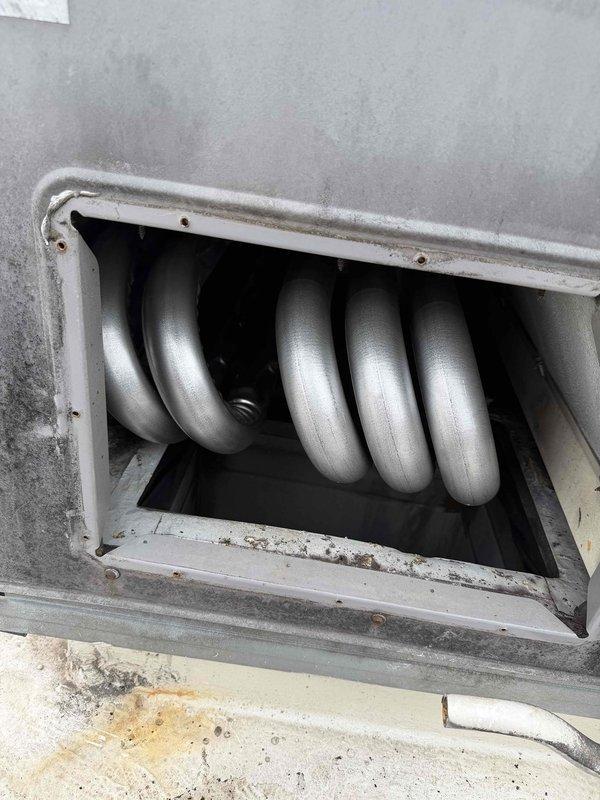 Removed and replaced failed heat exchanger in commercial HVAC unit. Accessed unit through wall-mounted service panel, extracted existing heat exchanger assembly showing signs of deterioration, and installed new serpentine-style tubular heat exchanger with proper mounting and alignment. Verified secure installation within unit housing, confirmed all connections, and restored unit to operational status.