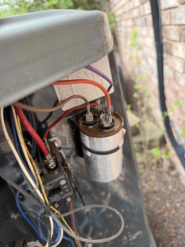 Responded to no cooling complaint with system blowing warm air. Performed diagnostic evaluation of outdoor condensing unit and indoor air handler. Found capacitor showing signs of corrosion and age-related deterioration with rust visible on terminals. Measured system amperage at 7.58 amps using clamp meter to verify compressor operation and electrical performance. Inspected contactor, wiring connections, and electrical components for proper function and identified need for capacitor replacement due to visible deterioration affecting system performance.