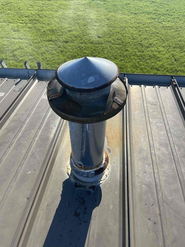 Responded to no heat callback on commercial rooftop unit. Upon arrival, inspected heating system and found unit would not maintain operation when thermostat override was attempted. Performed diagnostic evaluation of rooftop equipment, examined vent stack and flashing assembly which showed significant rust corrosion and weathering at roof penetration point. Documented existing conditions of exhaust vent pipe and rain cap assembly with visible deterioration affecting system components. Unit requires further assessment to determine root cause of recurring heating failure and restore reliable operation.