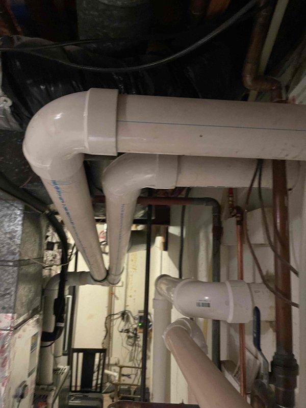 Responded to service call regarding disconnected ductwork ventilation issue. Upon arrival, inspected HVAC system and associated ductwork in basement utility area and exterior mechanical installation. Located disconnected PVC ventilation piping in crawl space area with complex configuration of drainage and ventilation components. Documented existing conditions with photographs showing PVC pipe routing through utility space alongside copper plumbing lines and HVAC infrastructure. Exterior inspection revealed condensate drainage system with U-trap configuration running between HVAC unit and building exterior. Advised property owner and contractor present on-site of findings and recommended proper reconnection of ventilation ductwork to ensure system operates according to manufacturer specifications and code requirements.