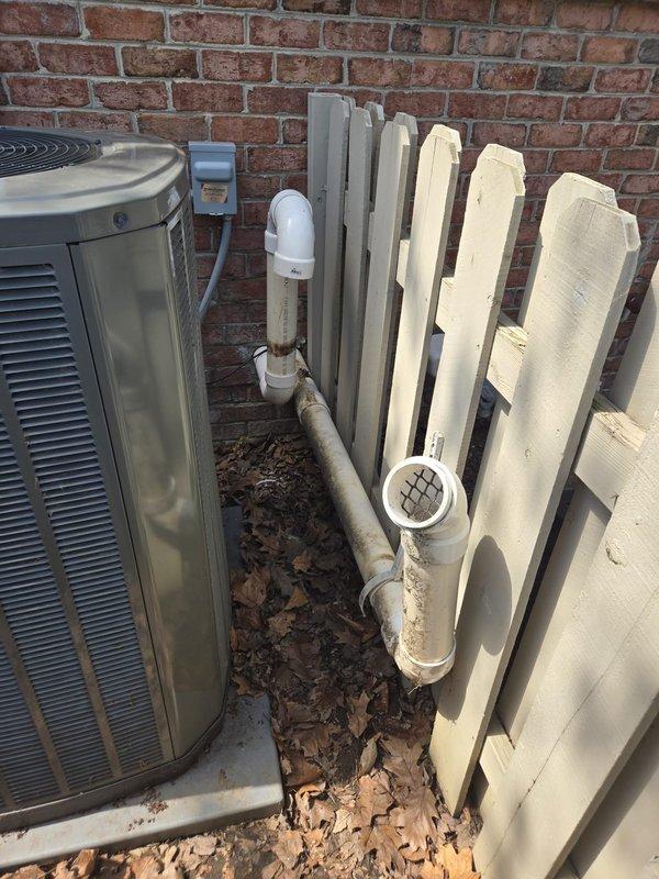 Completed repair work on residential HVAC system including outdoor condenser unit and associated condensate drain piping. Addressed drainage system components with white PVC piping secured to exterior brick wall, ensuring proper function and mounting. Inspected crawl space plumbing infrastructure and insulation conditions to verify system integrity.