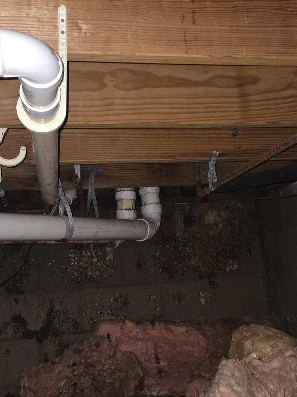 Completed repair work on residential HVAC system including outdoor condenser unit and associated condensate drain piping. Addressed drainage system components with white PVC piping secured to exterior brick wall, ensuring proper function and mounting. Inspected crawl space plumbing infrastructure and insulation conditions to verify system integrity.