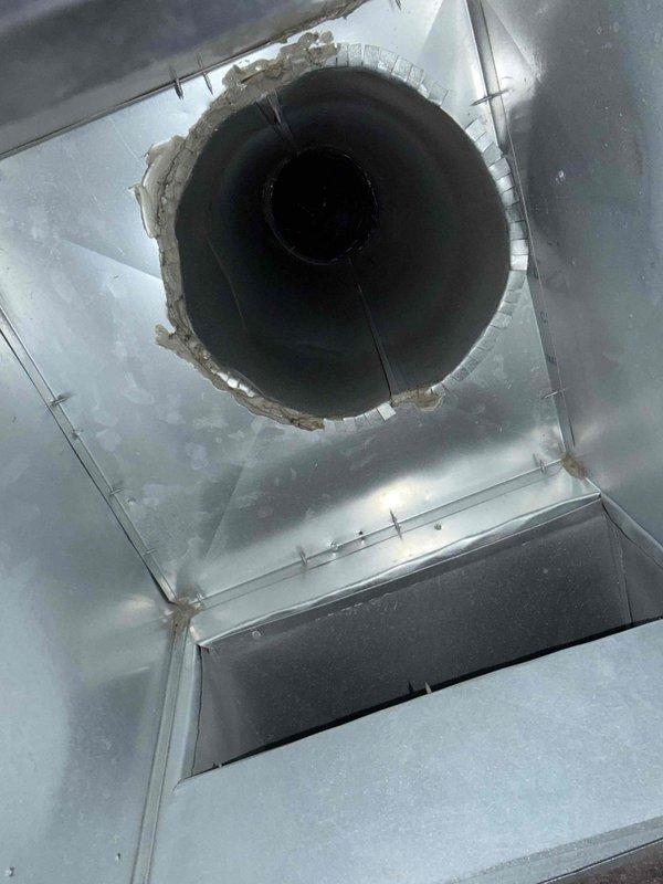 Responded to no cooling complaint on new HVAC system. Upon inspection, discovered supply plenum had inadequate or improperly sealed duct connection at the circular trunk line transition. Measured and verified airflow deficiency using digital instrumentation at the ductwork interface where metallic flex duct showed visible separation and compromised sealing at the plenum chamber. Identified that insufficient airflow distribution was caused by the disconnected or poorly fitted duct connection preventing conditioned air from reaching living spaces. Corrected the duct connection, ensuring proper seating and sealed all joints at the plenum transition point to restore full system airflow and cooling capacity.