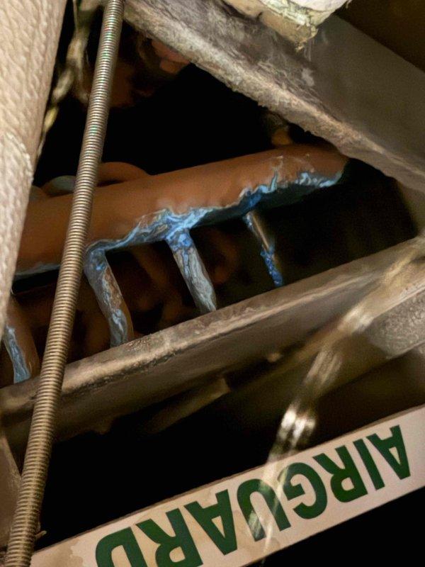 Responded to no-cool call for commercial chiller system. Found extensive frost accumulation on refrigerant lines and evidence of significant corrosion on system components, indicating refrigerant leak and moisture intrusion. Documented conditions with photos showing ice buildup on copper piping in ceiling cavity and severe corrosion with copper oxidation patina on metal surfaces around pipe penetrations.