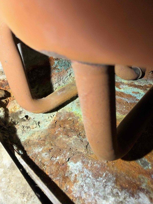 Responded to no-cool call for commercial chiller system. Found extensive frost accumulation on refrigerant lines and evidence of significant corrosion on system components, indicating refrigerant leak and moisture intrusion. Documented conditions with photos showing ice buildup on copper piping in ceiling cavity and severe corrosion with copper oxidation patina on metal surfaces around pipe penetrations.