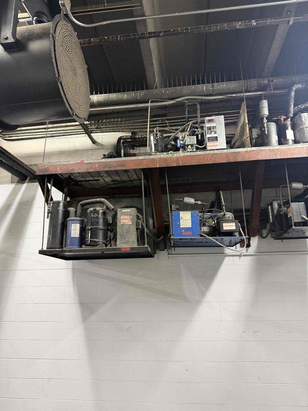 Responded to no cooling complaint at commercial facility. Performed diagnostic evaluation of multi-compressor HVAC system mounted on elevated platform with associated ductwork and refrigeration components. Documented equipment condition and configuration including multiple compressor units, refrigerant lines, and control systems. Provided comprehensive assessment of system status and presented repair versus replacement options to management for decision-making purposes.