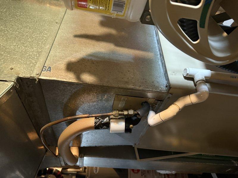 Completed on-site evaluation of existing HVAC system located in residential utility area for air conditioning replacement estimate. Assessed current furnace unit with connected PVC condensate drainage, existing ductwork configuration, and available installation space in basement mechanical room. Documented existing copper refrigerant lines, condensate piping connections, and electrical service to prepare comprehensive replacement proposal for new air conditioning system installation.