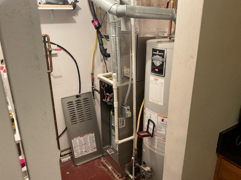 Responded to no cooling complaint on aging HVAC system located in basement utility room. Upon arrival, performed diagnostic evaluation of furnace and air handler unit with associated ductwork and refrigerant lines. System showed signs of age-related wear consistent with 10+ year old equipment struggling to maintain adequate cooling capacity during warmer weather conditions. Documented existing equipment configuration including furnace unit, metallic supply ductwork, copper refrigerant lines, and electrical connections for assessment of repair versus replacement options.