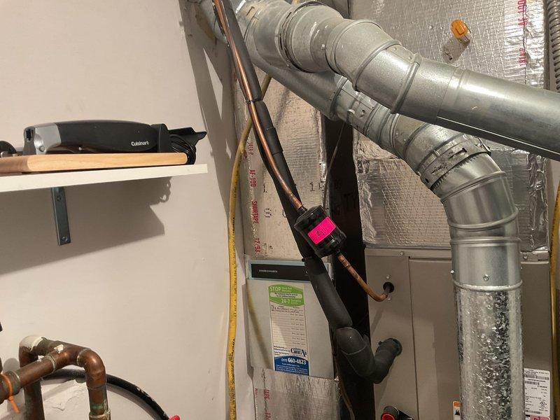 Responded to no cooling complaint on aging HVAC system located in basement utility room. Upon arrival, performed diagnostic evaluation of furnace and air handler unit with associated ductwork and refrigerant lines. System showed signs of age-related wear consistent with 10+ year old equipment struggling to maintain adequate cooling capacity during warmer weather conditions. Documented existing equipment configuration including furnace unit, metallic supply ductwork, copper refrigerant lines, and electrical connections for assessment of repair versus replacement options.