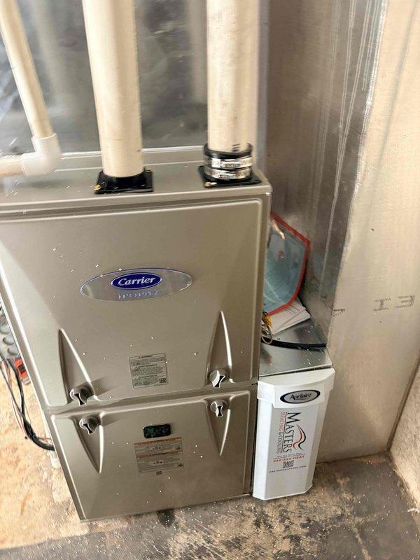 Completed full HVAC system installation in residential basement utility room, including Carrier brand furnace unit with proper venting configuration. Installed white PVC intake and exhaust pipes extending from unit top, secured with mounting brackets per manufacturer specifications. Integrated REME HALO air purification system mounted to furnace cabinet with appropriate electrical connections. Connected all ductwork and verified proper airflow throughout system. Obtained required financing paperwork signatures and discussed extended maintenance plan options with homeowner, who declined due to future home sale plans within four years.