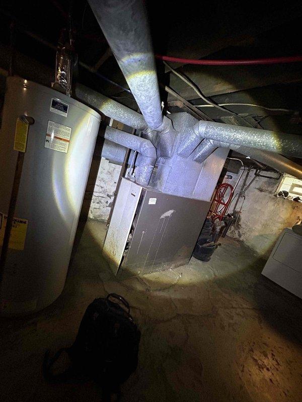 Conducted comprehensive assessment of existing HVAC system in older residential property requiring full system replacement estimate. Evaluated aging furnace unit with exposed blower motor assembly and existing ductwork infrastructure throughout basement utility area. Documented current equipment condition including oversized legacy furnace, existing metal ductwork with insulated branch configurations, and filter housing assembly. Customer seeking complete heating and cooling system replacement for home that has never had air conditioning installed. Provided detailed measurements and photographic documentation of mechanical room layout, existing duct runs, available installation space, and utility connections to prepare accurate replacement system proposal incorporating new furnace and air conditioning components utilizing existing ductwork where feasible.