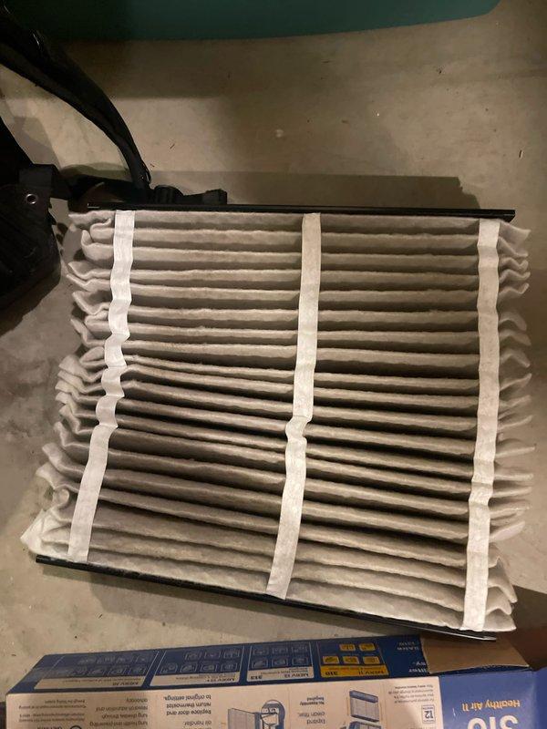 Completed air conditioning tune-up service on residential HVAC system. Inspected existing air filter which showed moderate dust accumulation and discoloration from normal use. Installed new pleated air filter in system housing to ensure proper airflow and filtration efficiency for optimal system performance.