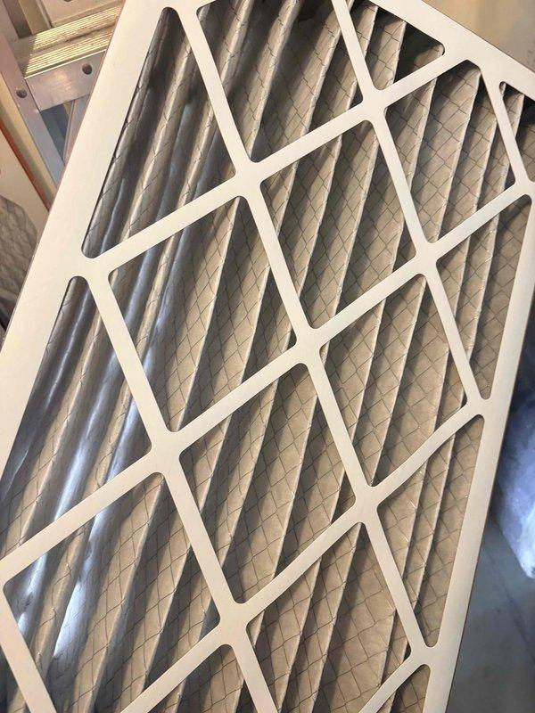 Completed first seasonal cooling maintenance inspection on residential HVAC system. Inspected air filter located in attic space, noting moderate dust accumulation on pleated media with filter remaining serviceable. Documented filter condition with photos showing diagonal grid reinforcement structure and accordion-style pleated construction functioning properly.