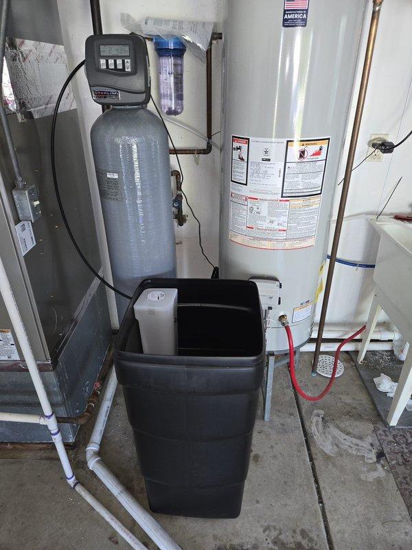 Installed new water softener system with digital control head and brine tank in utility room, connecting all necessary water supply lines and drain connections. Upgraded existing laundry sink drain line from current size to 1-1/2 inch PVC, routing it properly to the floor drain to accommodate increased water discharge from the new softener system during regeneration cycles.