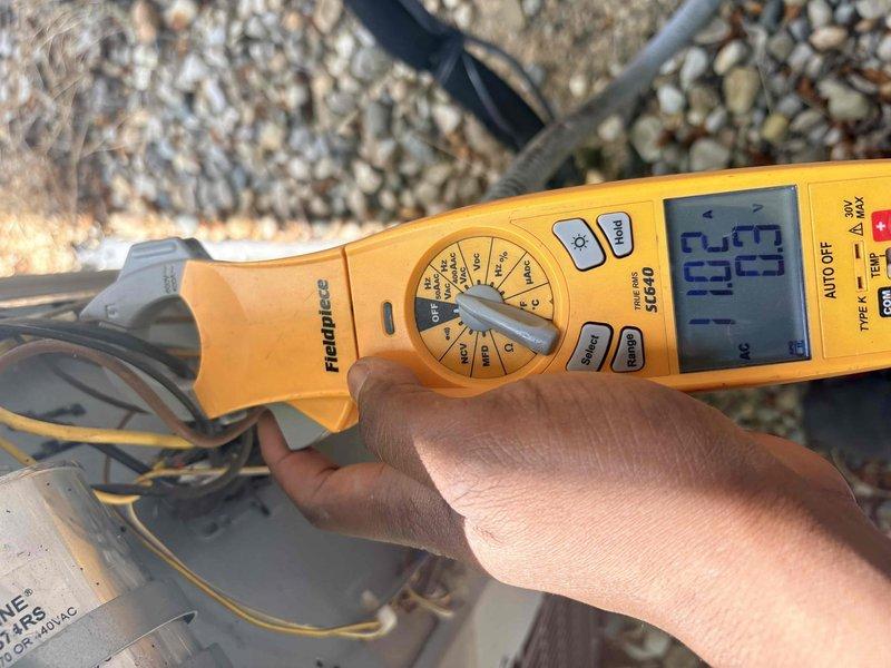 Completed air conditioning tune-up on rooftop unit. Performed electrical measurements using clamp meter, recording voltage and amperage readings at 24.3 amps. Inspected condenser fan motor assembly, verified proper operation of motor shaft and cooling fins, and confirmed all components functioning within normal parameters.