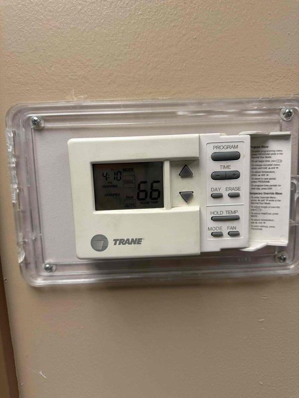 Responded to no heat or cool complaint in Industrial Engineering office on 2nd floor B Wing. Performed diagnostic inspection of HVAC system and thermostat controls. Inspected Trane programmable thermostat with protective cover showing display reading 66 degrees and 4:10 time, confirmed all control buttons operational. Examined red electronic control panel mounted on wall with LCD display and control functions for SCROLL, RESET, and MORE buttons. Documented system components and current settings with photos for repair cost estimation and approval process prior to completing necessary repairs.