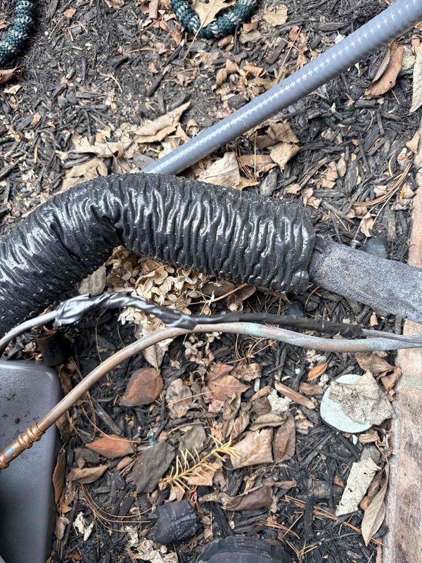 Responded to callback regarding exposed wiring visible at exterior installation site. Inspected refrigerant line set with black insulation wrap and associated electrical wiring running along foundation near wall penetration. Secured and properly concealed exposed control wiring in conduit to address safety concerns and ensure installation meets code requirements.
