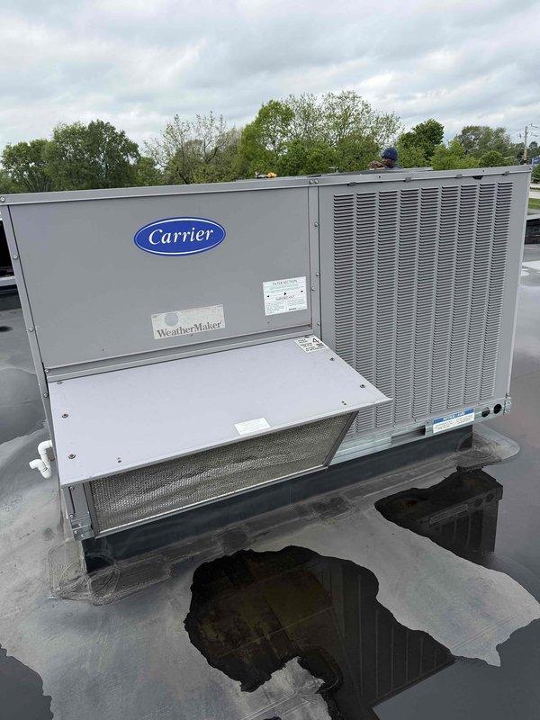 Performed diagnostic evaluation on two commercial HVAC units experiencing cooling failures. First unit servicing cafe area exhibited no cool air output; inspection revealed suspected evaporator coil leak requiring further assessment. Second unit, a Carrier WeatherMaker rooftop package unit, displayed abnormal amperage readings and heavily soiled condenser coils compromising heat rejection efficiency. Documented equipment conditions with photographic evidence showing indoor evaporator assembly with air filter in place and rooftop unit with visible water pooling around base. Recommended comprehensive repair quote for both units including evaporator coil replacement or repair on first system and condenser coil cleaning with electrical diagnostics on second unit, along with proposed four-visit annual maintenance agreement to prevent future failures.