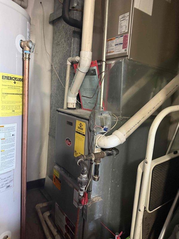 Responded to no heat call on aging HVAC system. Upon arrival, performed complete system diagnostic including visual inspection of furnace unit, gas supply line, and associated components. Verified gas supply valve operation at exterior meter, confirmed proper positioning and functionality of shut-off valve, and inspected gas piping for leaks or damage. Conducted thorough assessment of furnace including ignition system, burner assembly, heat exchanger, blower motor, and safety controls. Documented equipment condition with photos showing exterior gas line assembly with age-related weathering and interior furnace installation with connected water heater. System restored to proper operation and tenant advised of findings.