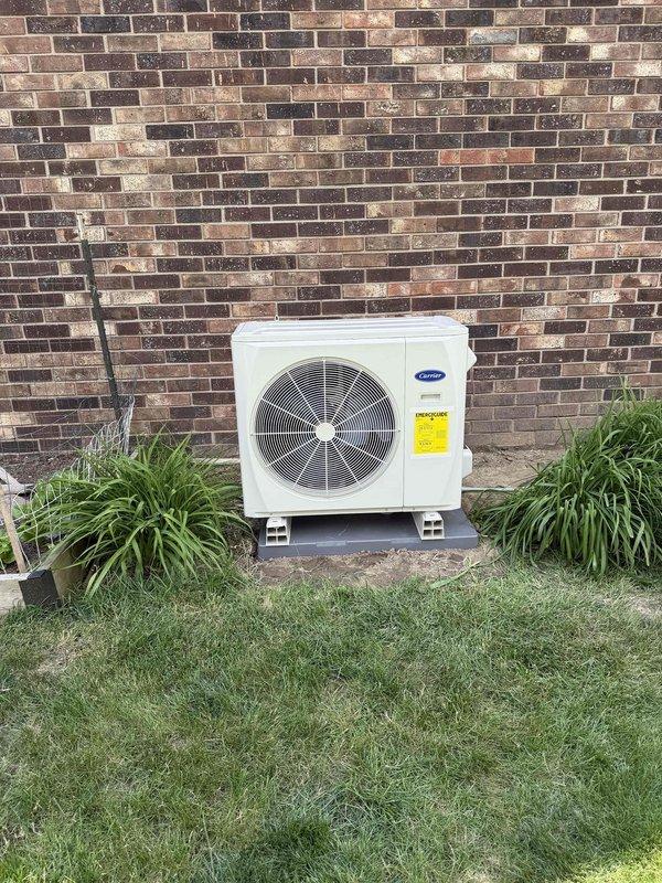 Completed full HVAC system installation including outdoor Carrier condensing unit mounted on composite support blocks against exterior brick wall. Installed refrigerant line set with proper insulation routed along wall to indoor air handler. Mounted electrical disconnect box on exterior wall with appropriate conduit protection for power supply. System installed per manufacturer specifications with all components properly secured and connected. Verified proper refrigerant charge, tested electrical connections, and confirmed operational performance of complete heating and cooling system.