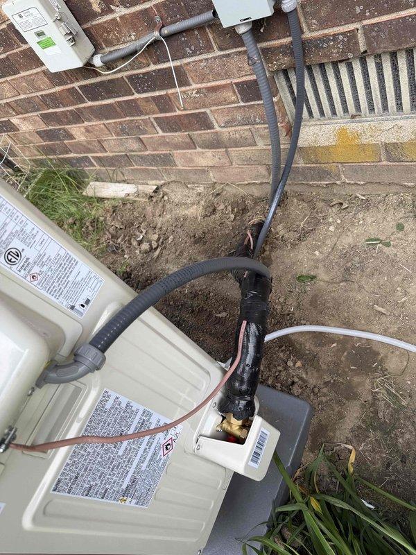 Completed full HVAC system installation including outdoor Carrier condensing unit mounted on composite support blocks against exterior brick wall. Installed refrigerant line set with proper insulation routed along wall to indoor air handler. Mounted electrical disconnect box on exterior wall with appropriate conduit protection for power supply. System installed per manufacturer specifications with all components properly secured and connected. Verified proper refrigerant charge, tested electrical connections, and confirmed operational performance of complete heating and cooling system.