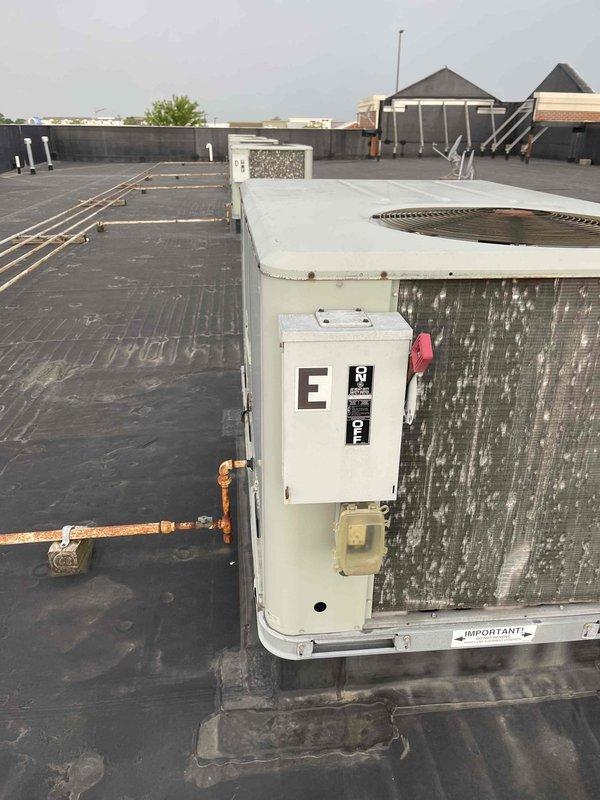 Conducted site assessment of three rooftop units (RTUs) at commercial retail facility to provide replacement estimates as requested by property management. Inspected all three units, documented existing equipment conditions including weathered casings, electrical disconnects labeled "E" and "F", and noted significant corrosion on copper refrigerant and gas lines. Photographed equipment showing age-related deterioration and confirmed rooftop access for future replacement work.