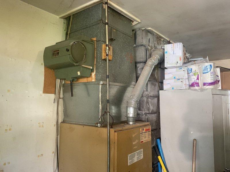 Completed comprehensive estimate for full HVAC system replacement at residential property. Assessed existing Lennox outdoor condensing unit with significant vegetation overgrowth obstructing airflow and indoor air handling unit with green-painted cabinet installed in utility space with connected ductwork. Documented current system conditions including outdoor unit surrounded by dense weeds and indoor equipment configuration to provide replacement recommendations for complete heating and cooling system upgrade.