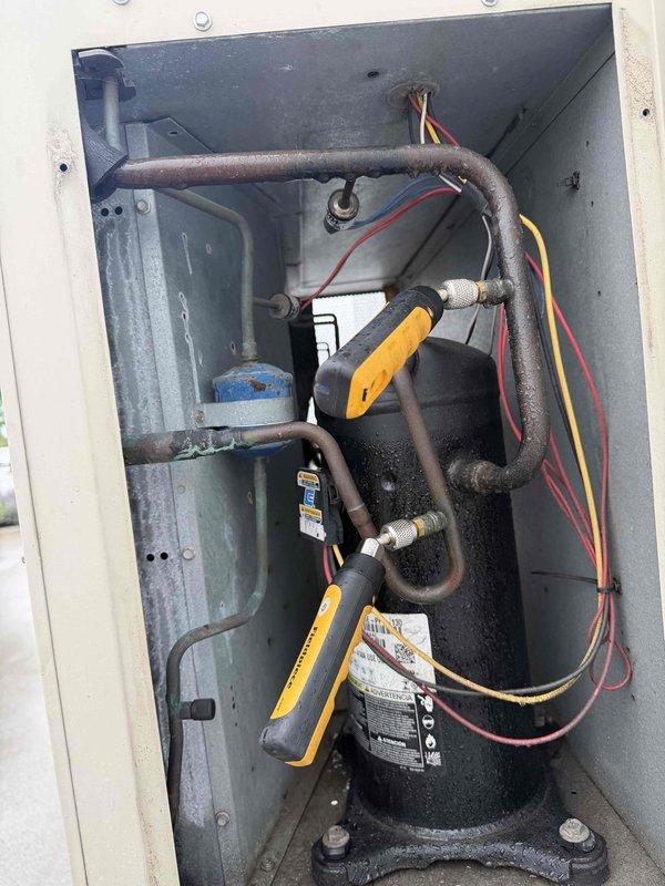 Responded to no cooling complaint on commercial packaged HVAC unit mounted on exterior building wall. Upon arrival, verified unit was running but not providing cooling to conditioned space. Accessed compressor compartment and performed diagnostic testing using clamp meter on refrigerant lines and electrical components. Inspected compressor, refrigerant piping, insulation integrity, and electrical connections. Documented equipment condition with photos showing Satell-ite branded unit and internal components. Provided diagnostic findings and repair recommendations to authorized contact for approval.