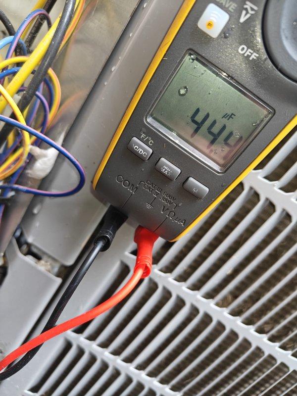 Completed comprehensive AC tune-up including full system inspection and diagnostics. Tested capacitor with multimeter, reading 44 microfarads within acceptable range for proper compressor operation. Inspected air filtration system, noting pleated filter condition and ductwork connections, with all components functioning properly and system operating efficiently.