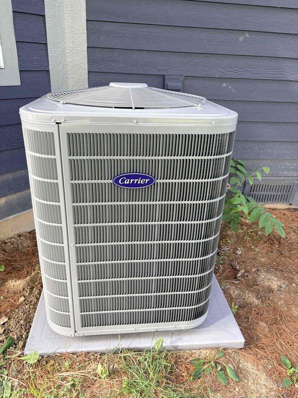 Completed full HVAC system installation including new Carrier outdoor condensing unit positioned on concrete pad and Carrier smart thermostat with digital display. System commissioned and verified operational with thermostat programmed to 72°F cooling setpoint, confirming proper communication between indoor and outdoor components.