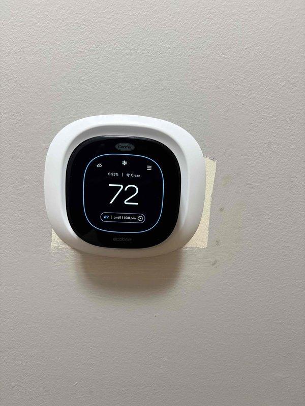 Completed full HVAC system installation including new Carrier outdoor condensing unit positioned on concrete pad and Carrier smart thermostat with digital display. System commissioned and verified operational with thermostat programmed to 72°F cooling setpoint, confirming proper communication between indoor and outdoor components.