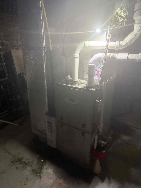 Responded to no cooling call on 6-year-old system with indoor unit failing to operate. Upon arrival, performed diagnostic evaluation of basement-installed HVAC equipment using electronic testing instruments. Inspected furnace/air handler unit and associated condensate drainage system including PVC piping and connections. Identified operational issue preventing indoor blower from engaging during cooling cycle. Documented equipment condition and system configuration with photographic evidence showing measurement device readings and overall installation layout. System requires repair to restore proper cooling function.
