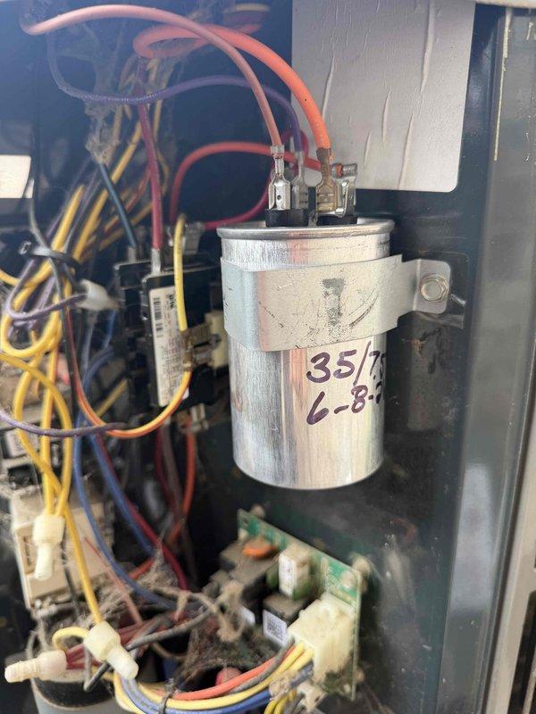 # HVAC No Cool Service Call

Responded to a no cool service call on a 14-year-old system located on the ground with air handler in a second-floor closet. Unit was not maintaining desired temperature. Upon arrival, performed system diagnostics and visual inspection of electrical components and air delivery system.

Accessed the air handler control panel and inspected the dual-run capacitor, which showed handwritten markings indicating 35/5 MFD ratings. Examined all electrical connections, wiring harness, and control board for signs of failure or deterioration. Evaluated the condition of the air return vents, which displayed normal dust accumulation consistent with system age and usage.

Tested capacitor for proper microfarad values and voltage ratings to determine if component failure was contributing to cooling loss. Inspected all wire connections at capacitor terminals and control board to ensure proper contact and no loose connections. Verified proper airflow through return air grill
