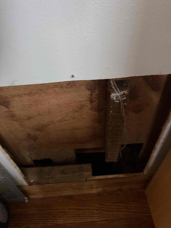 Responded to service call for newly installed unit experiencing freeze-up and inadequate temperature control. Instructed occupant to power down system and operate fan only to prevent further ice accumulation on evaporator coil. Upon inspection, documented crawlspace installation conditions showing evidence of significant moisture infiltration and water staining on structural members surrounding ductwork, which may contribute to ongoing humidity issues affecting system performance. Photographed evaporator coil assembly displaying dust accumulation on fins and insulation placement in mechanical space. Recommended allowing adequate thaw time before conducting diagnostic assessment of refrigerant charge, airflow restrictions, and potential drainage issues to determine root cause of freeze condition.