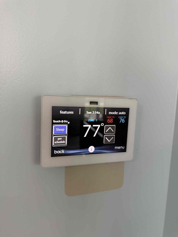 Installed white programmable thermostat with touchscreen display and multi-zone capability as requested. Configured system settings for Zone 1 with heating and cooling setpoints, programmed auto mode operation, and verified proper communication with HVAC equipment. Initiated duct assessment function to measure duct capacity for zoned system operation.