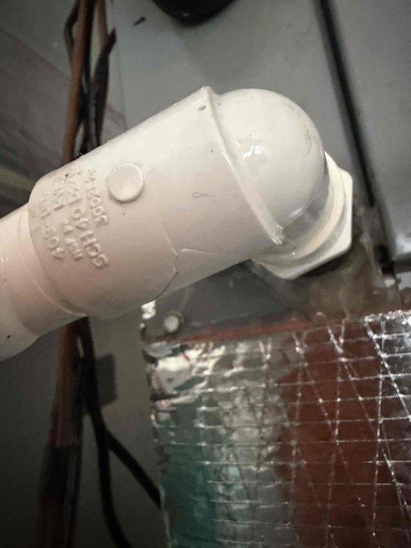 Responded to service call for residential HVAC system with damaged PVC condensate drain components. Replaced compromised section of drain line including male adapter, street 90 elbow fitting, and short pipe section to restore proper drainage function and prevent potential water damage to the mechanical room.