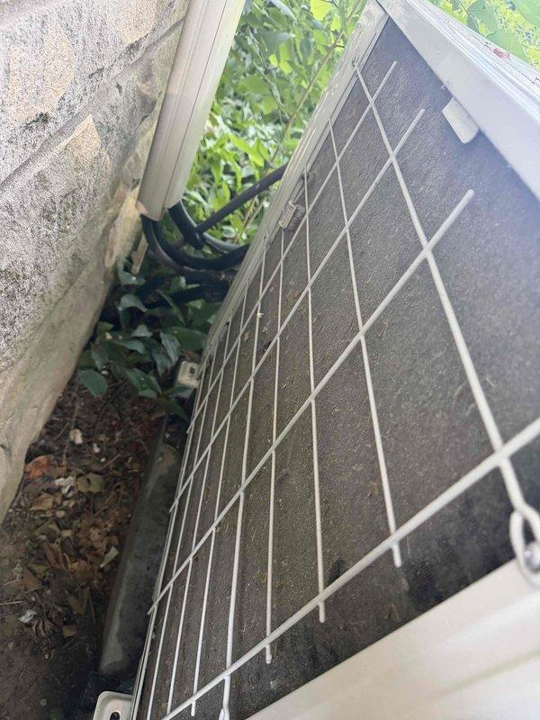 Completed AC tune-up on outdoor condenser unit. Unit was found operating with protective cage installed and positioned in confined space with surrounding vegetation. Inspected condenser coil and identified significant accumulation of dirt, dust, and biological growth across fin surfaces, causing reduced heat transfer efficiency. Performed standard maintenance procedures including system inspection and operational checks. Unit is functional but coil contamination may impact cooling performance if not addressed in future service.