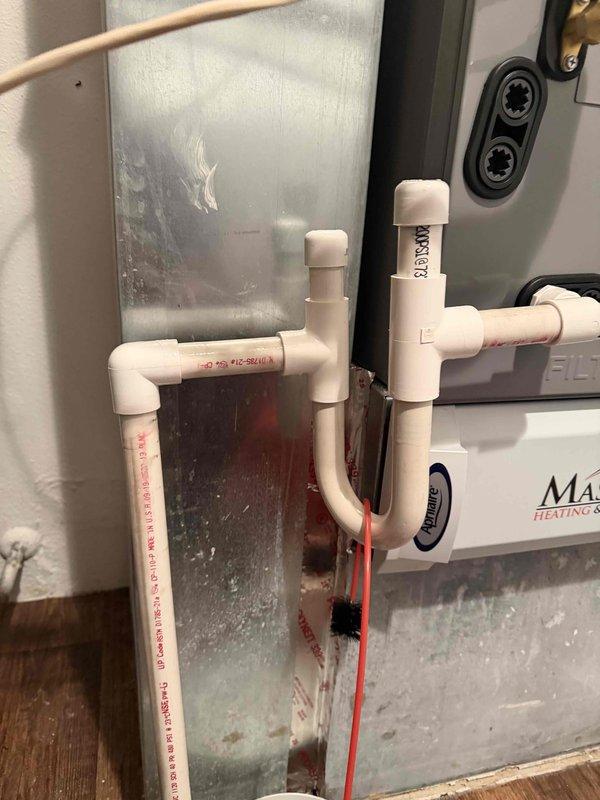 Responded to warranty callback for condensate drainage leak reported one day after installation. Upon inspection, identified active water leakage from PVC condensate line connections. Verified condensate drain system configuration including primary drain line with proper trap and secondary overflow provisions. Observed significant condensation accumulation on metal ductwork and equipment surfaces indicating active system operation. Repositioned collection container beneath leak point to prevent water damage to hardwood flooring. Inspected all PVC pipe joints, elbows, and glued connections throughout the drainage assembly for proper sealing and alignment. Tightened and resealed affected condensate line fittings to eliminate leak. Verified proper pitch and drainage flow through primary condensate system. Confirmed secondary safety pan and overflow protection functioning as designed. System tested and operating within manufacturer specifications with no further leakage detected at time of