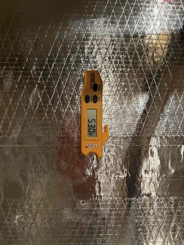 Completed installation of a new 5-ton Water Furnace 5-series geothermal heat pump system in basement mechanical room. System includes main heat pump unit mounted on concrete block wall with insulated refrigerant lines, supply and return ductwork with reflective insulation, electrical disconnect panel, and integrated controls. All ductwork connections sealed with metallic tape, PVC condensate drainage installed, and system startup procedures performed with temperature verification readings confirming proper operation at 530.3°F on heat mode testing.